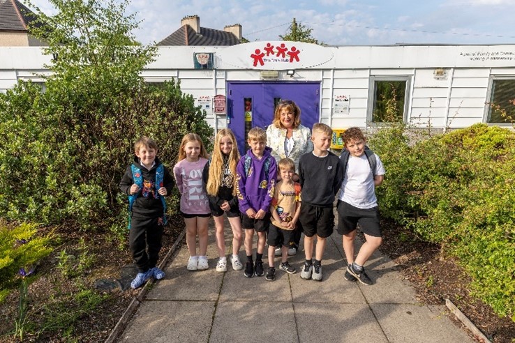 A group of children standing in front of a white building